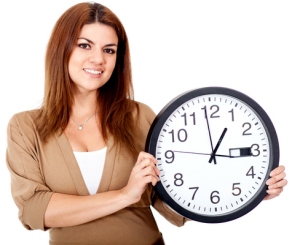 Woman holding a clock and smiling - isolated over a white background
